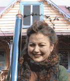 A wpman smiling and holding a solar tube in front of a heritage home.