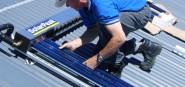 A man attaching a solar panel to a roof. 