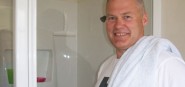 A man standing in front of his solar heated shower