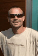 A man wearing sunglasses standing in the doorway of a new home. 
