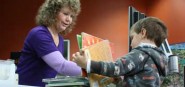 A librarian helping a boy check out books. 