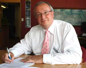 A smiling man sitting at his desk. 