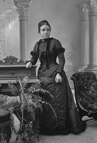 Black and white photo of Sophia Anstice standing in a dress. 