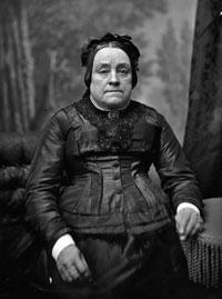 Black and white photo of Ann Bird standing in a dress. 