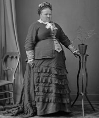Black and white photo of Susan Dalton standing in a dress. 