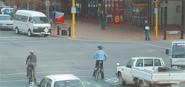A cyclist stopped at a red light next to a car. 