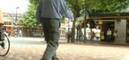 A man crossing a street on a raised brick path. 
