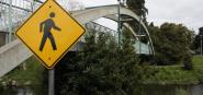 A pedestrian sign in front of a walkway bridge. 